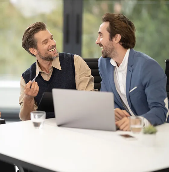 Duas pessoas a conversar sobre um projeto em frente a um portátil